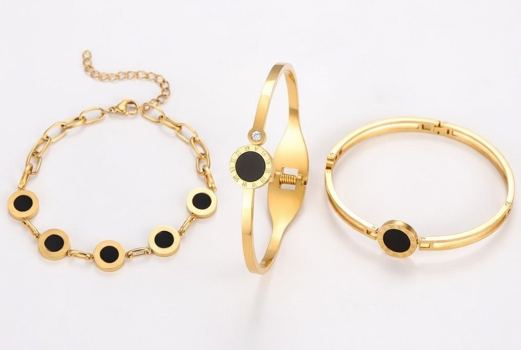Gold bracelet set with black accents on a white background